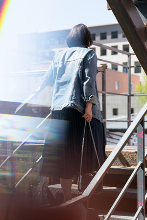 young beautiful woman posing in a blue denim jacket on the stairsの写真素材