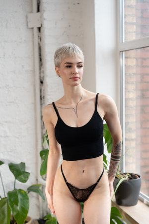 young beautiful girl posing in black lingerie in the studio on the windowsillの写真素材