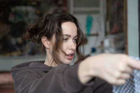 Young woman with long brown curly hair looking at the mirror and pointing with her fingerの写真素材