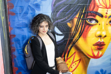 Portrait of a beautiful young woman in front of a graffiti wallの写真素材