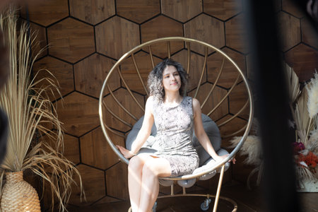 Beautiful woman sitting on a swing in a rustic interior.の写真素材