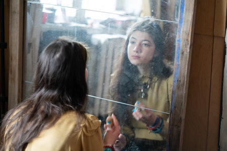 Young woman looking at the reflection in the mirror at rainy day.の写真素材