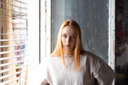 Portrait of a young red-haired girl in a white sweater.の写真素材