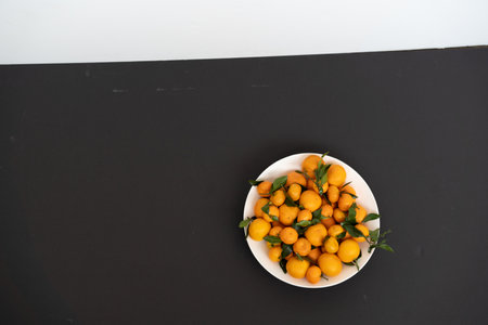 Tangerines in a white plate on a black background, top viewの写真素材