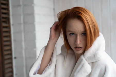 Young redhead woman with freckles in a white dressing gownの写真素材
