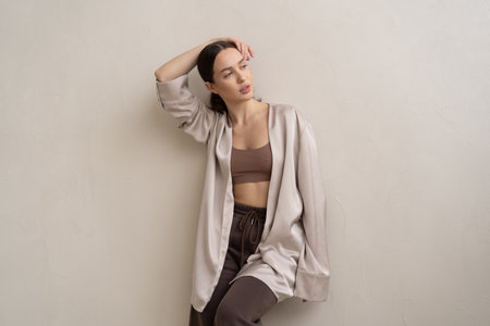 Portrait of a beautiful young brunette woman in a beige jacket and brown pantsの写真素材