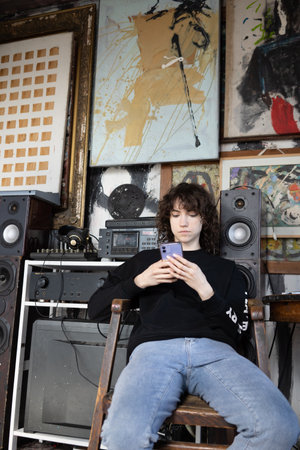Young woman listening to music with a mobile phone sitting in a chairの写真素材