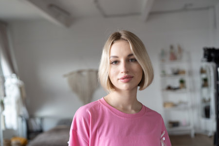Portrait of a beautiful young woman with blonde hair in a pink sweater.の写真素材
