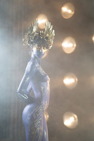Nude woman with golden crown on her head in front of lightsの写真素材