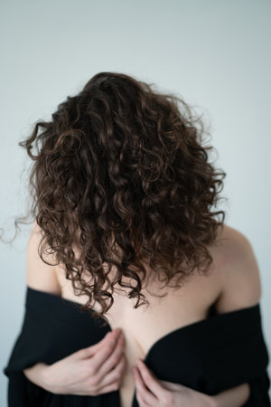 Portrait of a beautiful young woman in black dress with curly hairの写真素材
