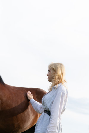 Beautiful woman with a horse on a background of blue sky.の写真素材