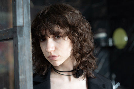 Portrait of a beautiful young girl with curly hair in a black dressの写真素材