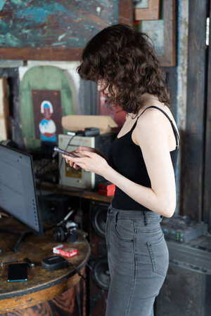 A young girl in a black T-shirt and gray jeans is using a smartphone.の写真素材