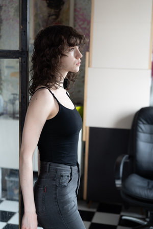 Portrait of a beautiful young woman with curly hair in black clothesの写真素材