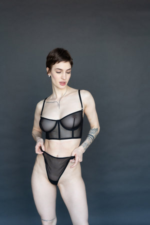 young beautiful girl posing in black lingerie in the studio on a gray backgroundの写真素材