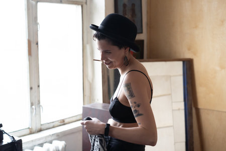 Beautiful girl in a black top and hat with a cigarette in her handsの写真素材