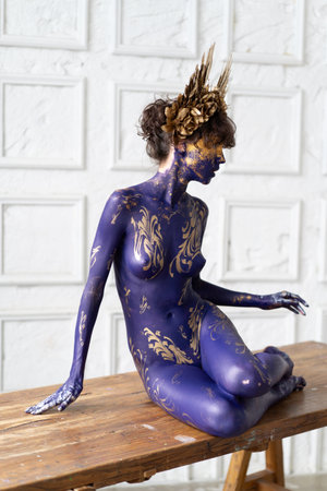 Naked woman with golden crown on her head, body painting.の写真素材
