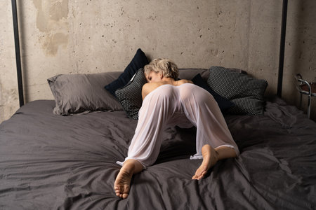blonde woman in pajamas sleeping on bed at homeの写真素材