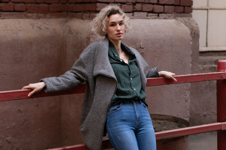 Portrait of a beautiful blonde girl in a gray coat and jeansの写真素材