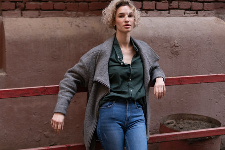 Portrait of a young beautiful girl in a coat and jeans on the street.の写真素材