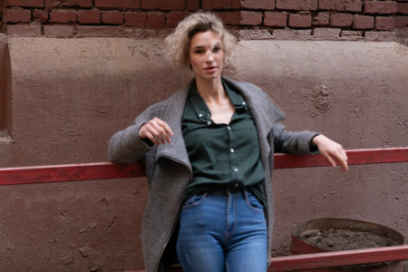 Young woman in a coat on a background of a red brick wallの写真素材