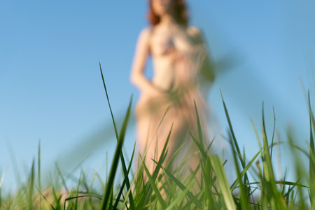 Blurred image of a woman in the grass on a background of blue skyの写真素材