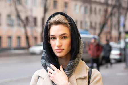 Portrait of a young beautiful woman in coat and scarf on the streetの写真素材