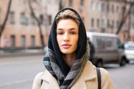 Portrait of a beautiful young woman wearing coat and scarf on the streetの写真素材