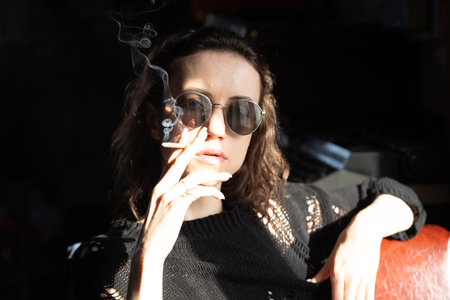 Portrait of a beautiful brunette woman in sunglasses with cigarette in handの写真素材