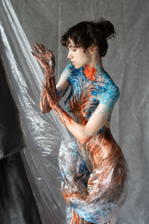 young beautiful girl posing in studio, covered with colored paint, body paintingの写真素材