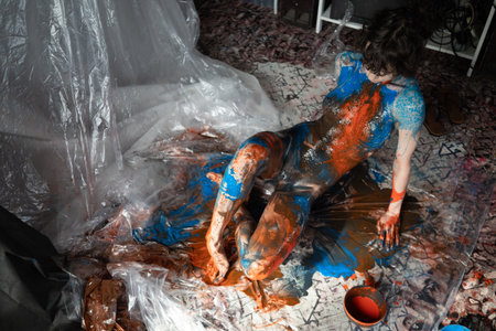 Young beautiful girl in a bright orange and blue paint on her bodyの写真素材