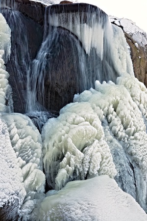 Water freezes while flowing down on a rockの写真素材
