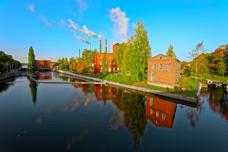 Old factory buildings of red brick by the canal at Myllysaari at sunny autumn day. Valkeakoski, Finlandの写真素材