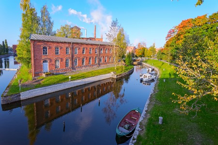 Old factory buildings of red brick by the canal at Myllysaari at sunny autumn day. Valkeakoski, Finlandのeditorial素材