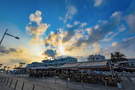 PAPHOS, CYPRUS - AUGUST 3, 2016: The busy promenade with many street cafes and bars at sunsetのeditorial素材