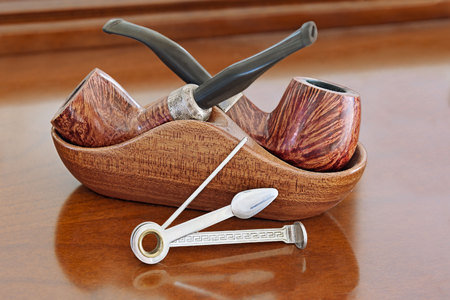 Tobacco smoking pipes and multifunctional cleaning gadget reamer tamper pokers on the wooden background.の写真素材