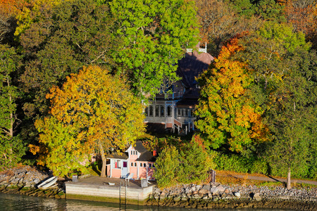 Small wooden jetty pier building on Turku Archipelago, in front of a log house in the autumn-coloured forest, Finlandの写真素材