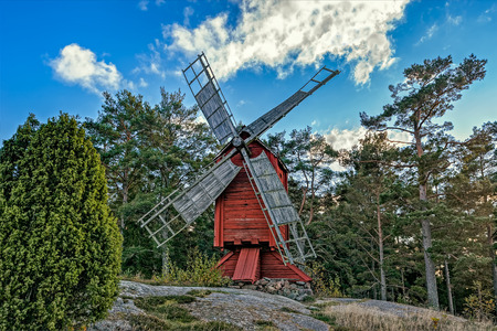 Red ochre colour wooden windmill in a old vintage rural landscape at Aland islands, Finland. Jan Karlsgarden open air museumのeditorial素材