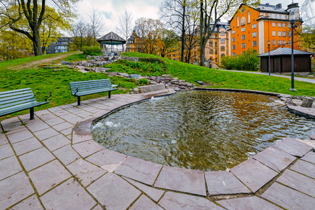 Wood made rustic benches facing a wonderful small pond shore in public Tegnerlunden park, Stockholm, Sweden.のeditorial素材