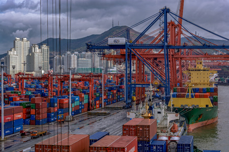 BUSAN, SOUTH KOREA - Dec 22, 2016: Sunrise panorama container cargo terminal of Port of Busan, Korea's busiest and the 10th-busiest in the world, in front of residential multistorey buildings.のeditorial素材