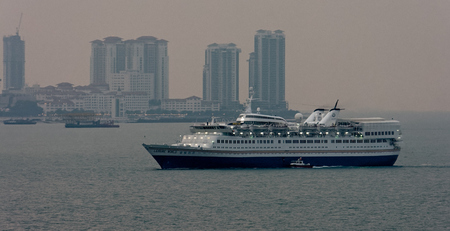 GEORGETOWN, MALAYSIA - Feb 02, 2017: Cruise passenger ship 'Leisure World' by New Century Tours Corp with night lights illuminate arrival to Swettenham Pier in the Georgetown harbor at sunset.のeditorial素材
