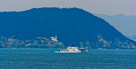 BUSAN, SOUTH KOREA - Jan 21, 2017: Korea coast guard boat next to Yeongdo Lighthouse and rocky coastline in Busan, South Korea.のeditorial素材