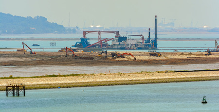 Dredging the sea fairway, panning shore and the beach to build a new commercial sea container terminal.の写真素材