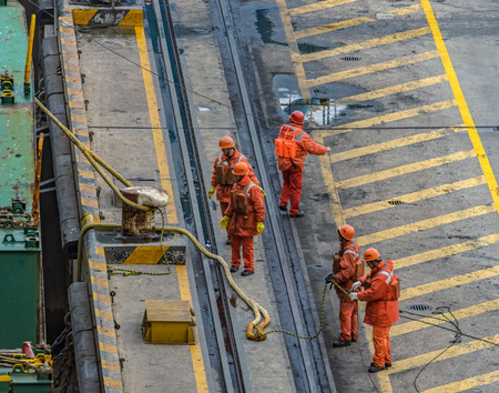 QINGDAO, CHINA - Apr 11, 2017: Longshoremen seen from above pulling a rope mooring container ship on Qingdao Qianwan Container Terminal.のeditorial素材