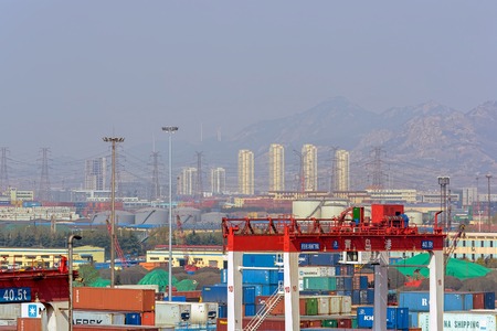 QINGDAO, CHINA - Apr 14, 2017: Qianwan container terminal with city skyline in the background at Qingdao.のeditorial素材