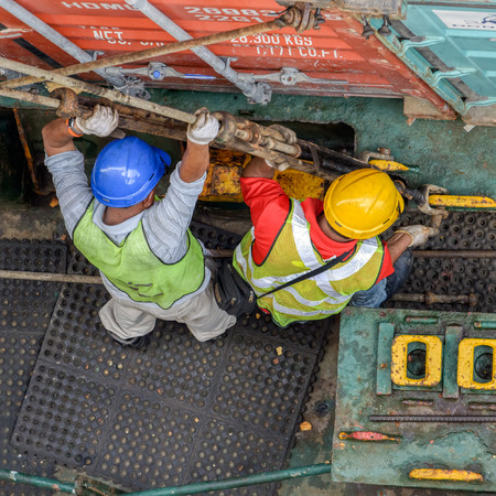PASIR GUDANG, MALAYSIA - Feb 02, 2017: Longshoremen uses long rods with turnbuckles to secure containers on an container ship in deck sockets.のeditorial素材