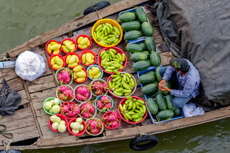 HO CHI MINH CITY (SAIGON), VIETNAM - April 25, 2017: Floating vendor from old style wooden river boat selling various fruits and snacks to cargo ship's crew. Elevated view from container ship board.のeditorial素材