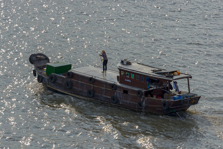 HO CHI MINH CITY (SAIGON), VIETNAM - Apr 25, 2017: Woman swabbing upper deck of old style wooden houseboat while sailing on river.のeditorial素材