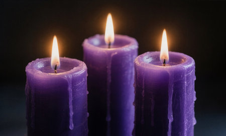 Three purple candles on a dark background. Shallow depth of field.の素材