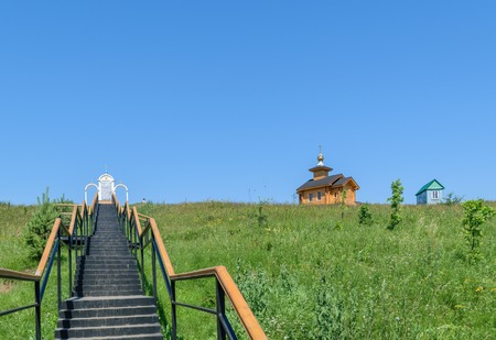 Metal stairs with railings leading up to the place of prayer and a wooden chapel near the small house on the hillの写真素材
